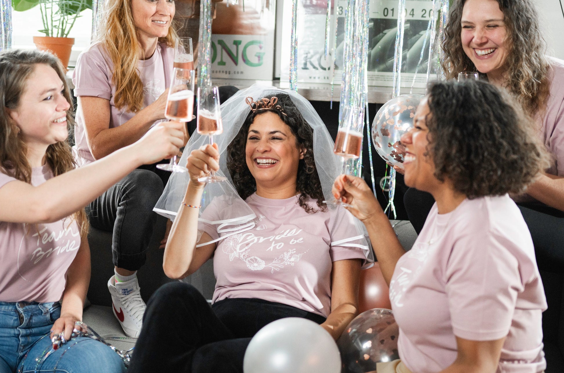 Cheers! Die Braut im BRIDE TO BE Shirt stößt mit ihren Freundinnen an.